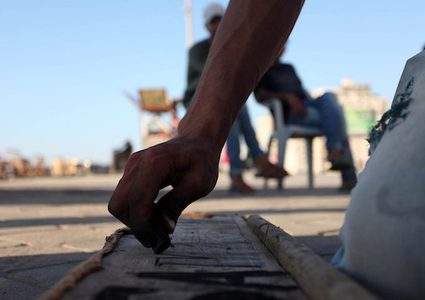 A young man from Gaza doing charcoal drawing on the sidewalk
