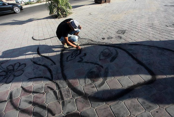 A young man from Gaza doing charcoal drawing on the sidewalk