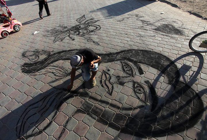 A young man from Gaza doing charcoal drawing on the sidewalk