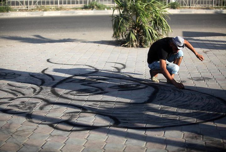 A young man from Gaza doing charcoal drawing on the sidewalk