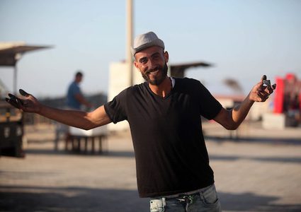 A young man from Gaza doing charcoal drawing on the sidewalk