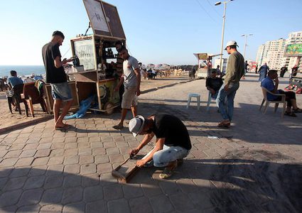 A young man from Gaza doing charcoal drawing on the sidewalk