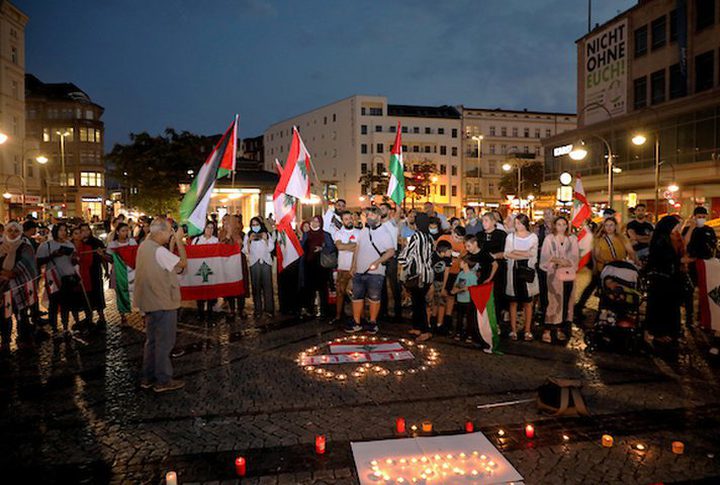 Palestinians and foreigners light candles to express their condolences to the Lebanese people while raising the Lebanese national flag, in Berlin, Germany, on August 8, 2020.